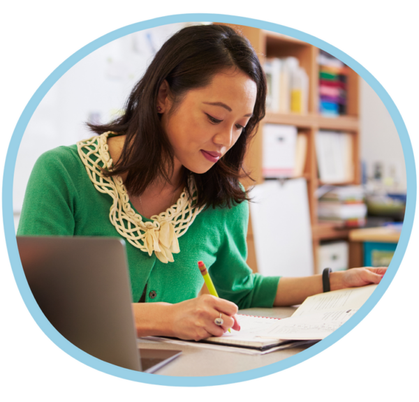 teacher at desk working on worksheets