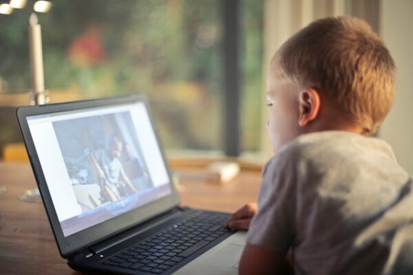 Child sitting in front of open laptop.