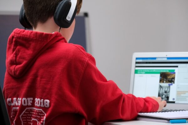 Boy with headphones in front of laptop.