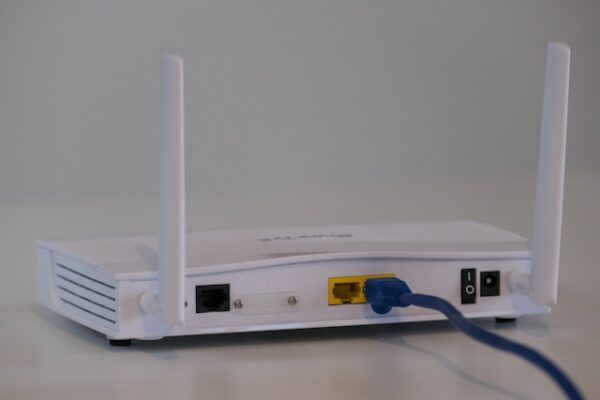 Broadband internet router with ethernet cable plugged in to the back in the ethernet port.